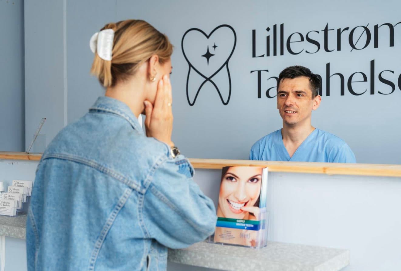 Pasient i resepsjonen hos Lillestrøm Tannhelse, med klinikkens logo på veggen